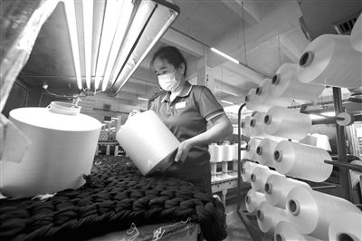 福建省晋江市福建锦兴集团员工在对涤纶加工丝产品进行合格检查.